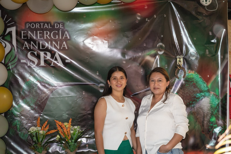 Dos visitantes frente a la lona de Portal de Energía Andina